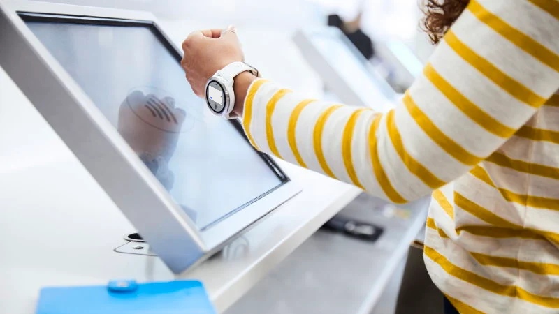 A woman at the airport making a payment with a watch