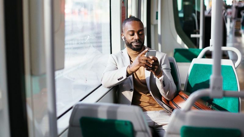Traveler in a suit using smartphone while sitting on a train.
