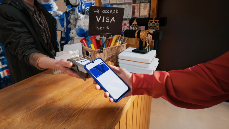Customer making contactless Visa mobile payment at a retail counter.