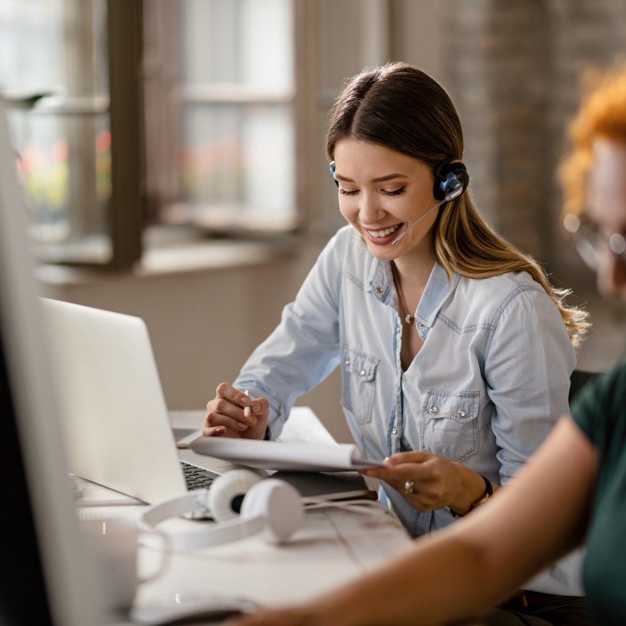 Customer support agent with headset working on laptop