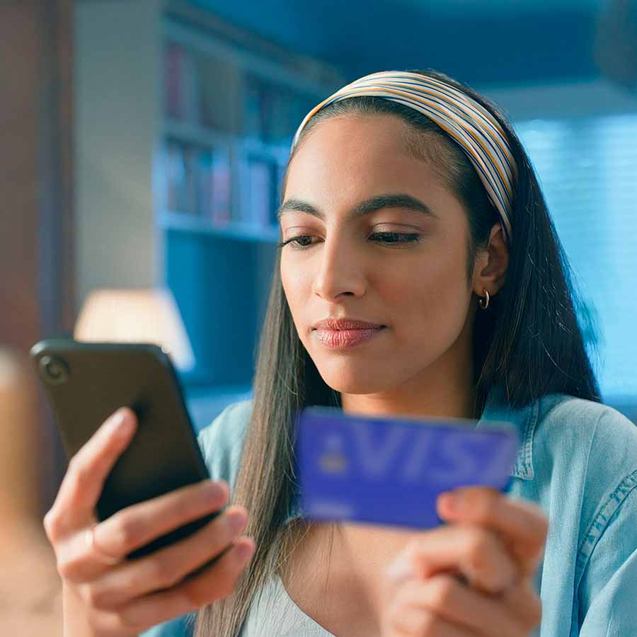 Woman holding phone and a Visa-branded card.