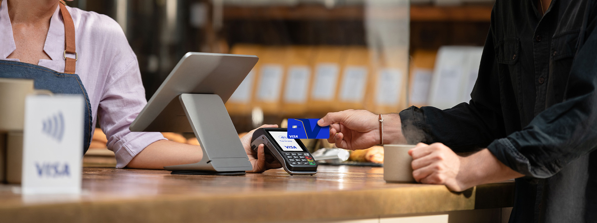Pessoa realizando pagamento contactless com cartão Visa azul